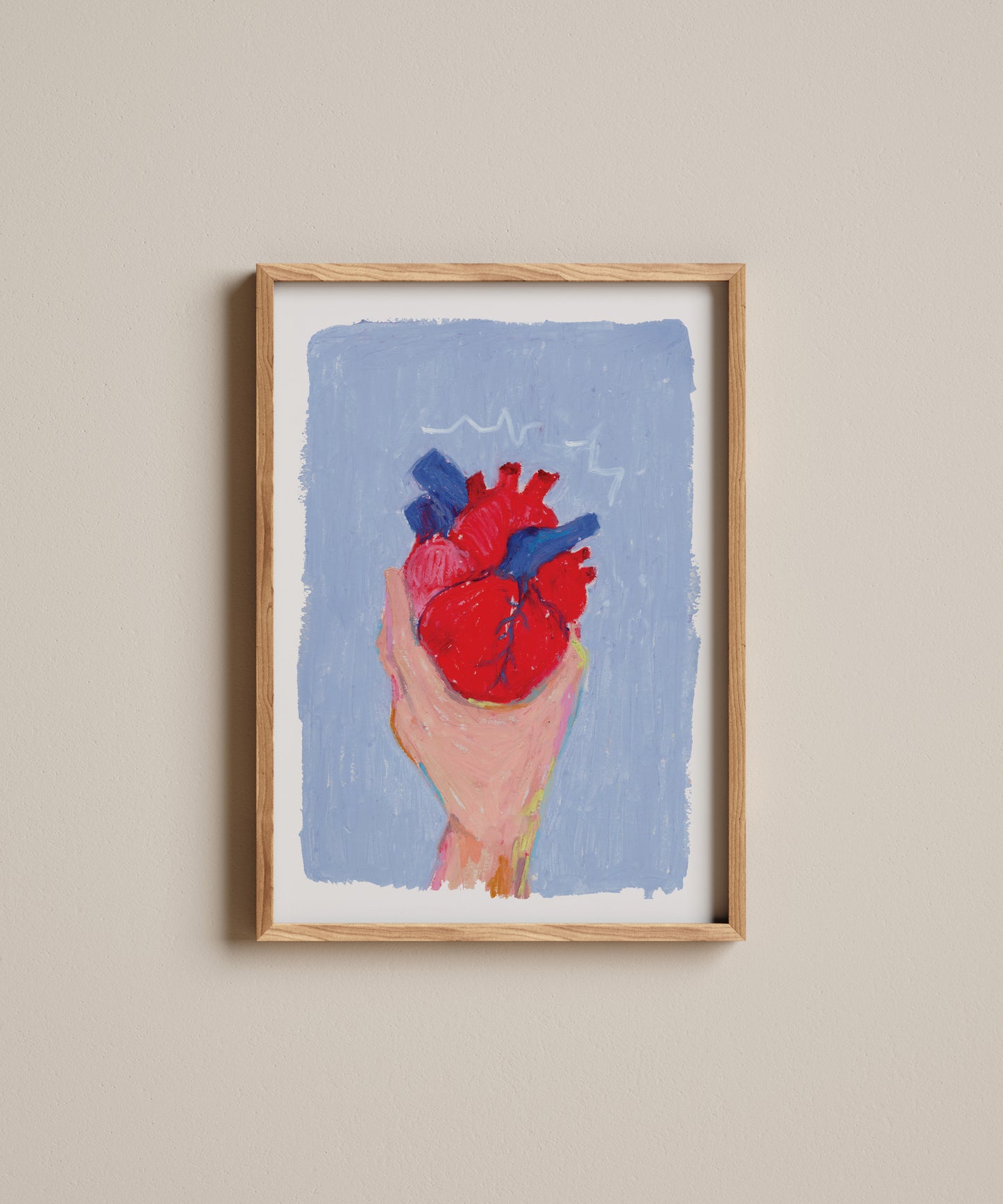 Framed artwork of a hand holding a red heart against a blue background on a beige wall.