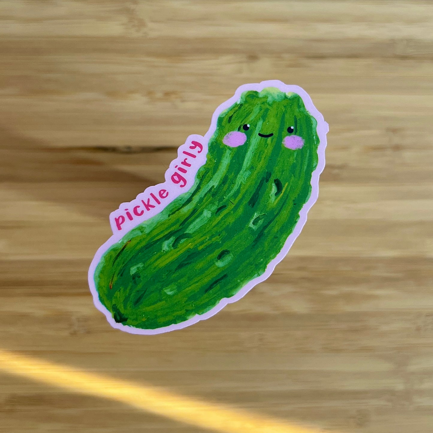 Sticker of a green pickle with a smiling face on a wooden surface