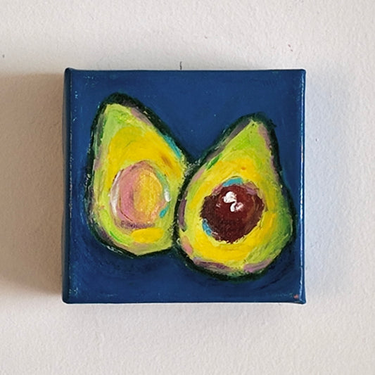 painting of sliced avocado on dark blue background hung on white wall