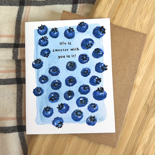 Greeting card with blueberry design and text on a wooden surface