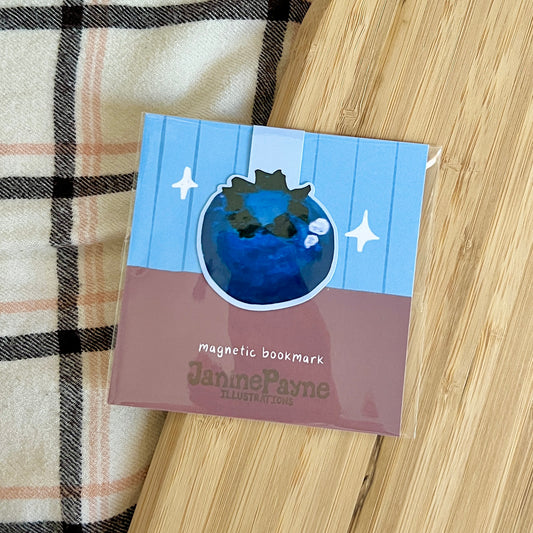 Magnetic bookmark with illustration on a wooden surface and plaid fabric background