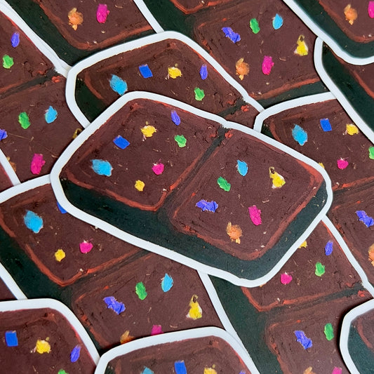 Close-up of chocolate brownie with colorful sprinkles on a green surface