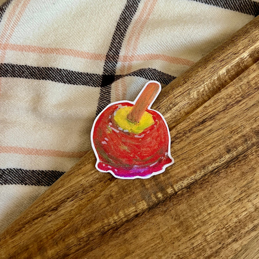 Sticker of a candy apple on a wooden surface with a plaid fabric background