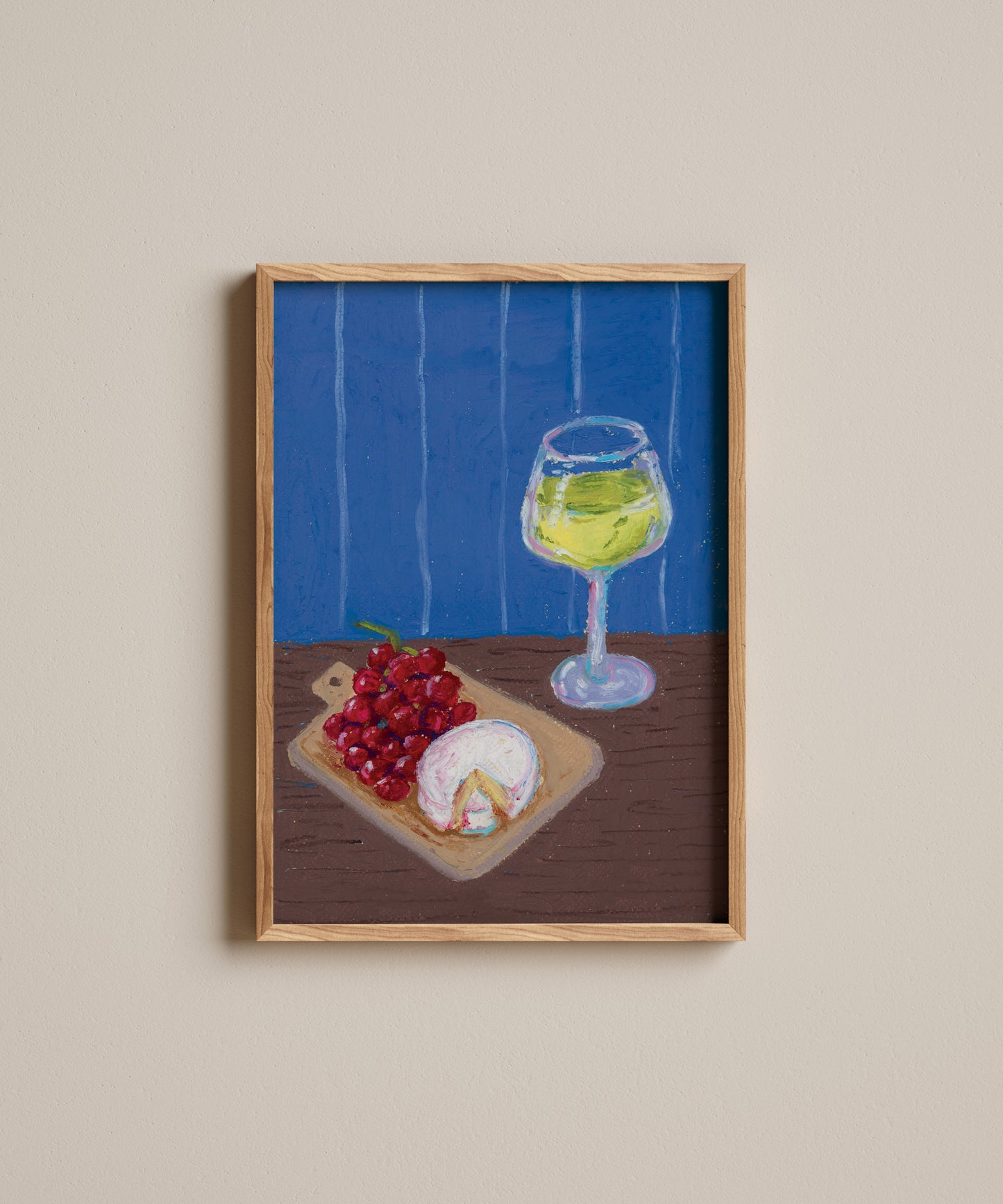 Framed artwork of a glass of white wine, grapes, and a piece of cheese on a wooden table with a blue background.