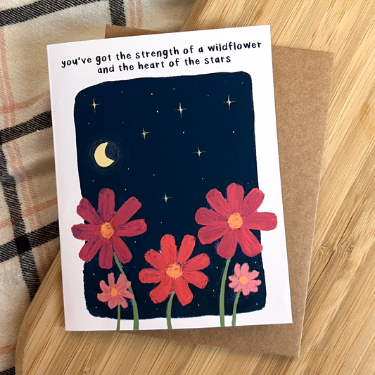 Greeting card with flowers and motivational quote on a wooden surface