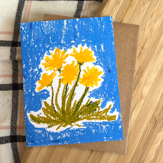 Card with yellow flowers on a blue background, placed on a wooden surface.