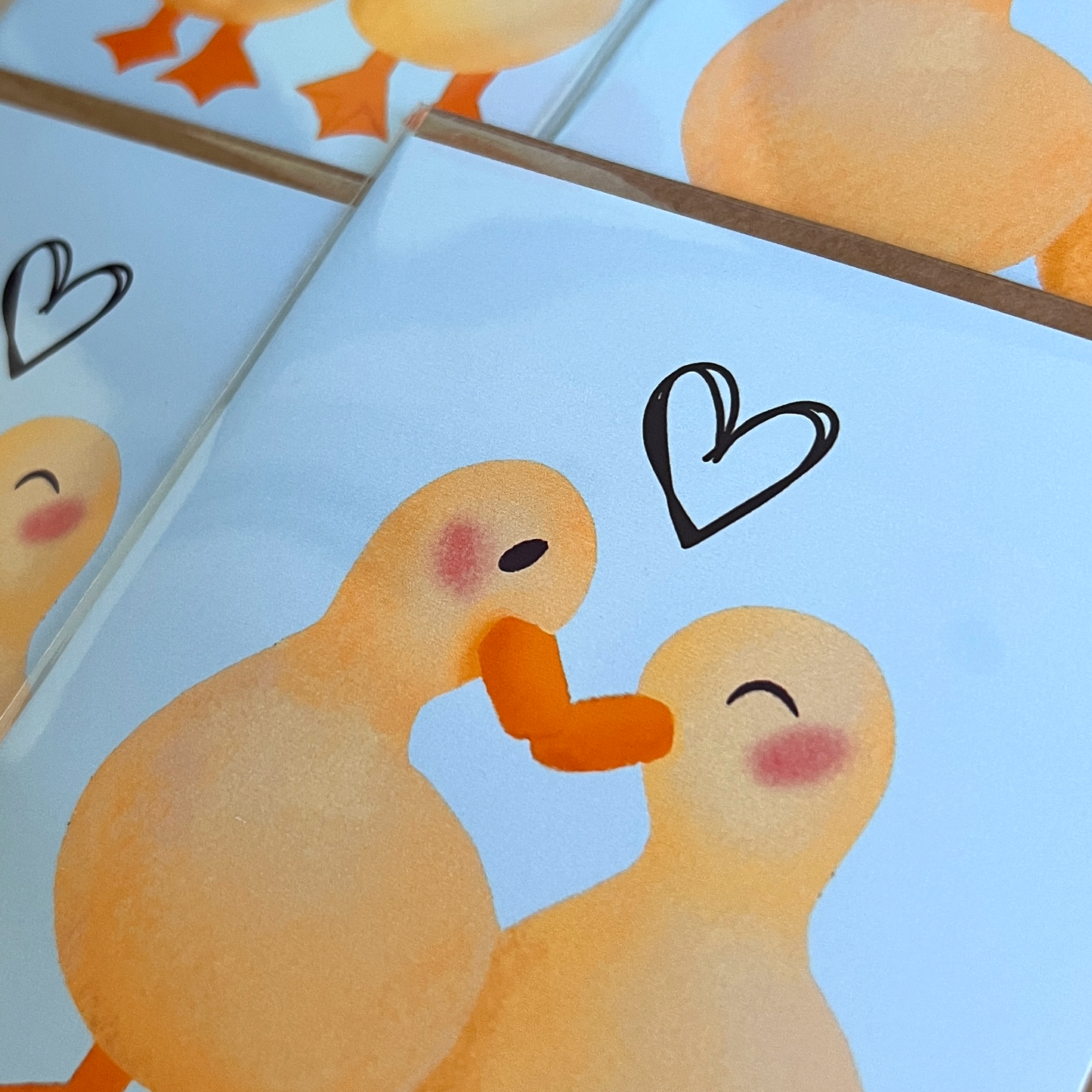 Cartoon ducks holding hands with a heart above them on a light blue background.