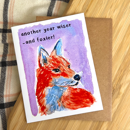 Greeting card with a fox illustration and text on a wooden surface