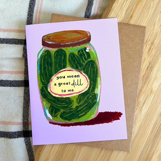 Greeting card with a jar of pickles illustration and text on a wooden surface.
