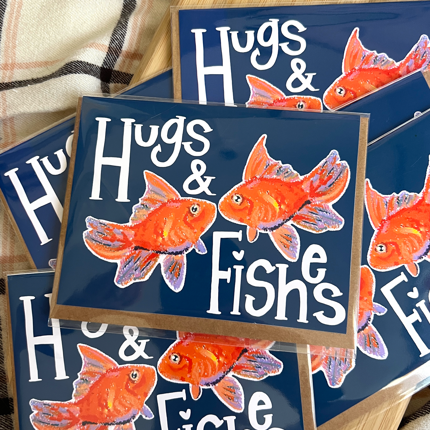 Greeting cards with goldfish and text 'Hugs & Fishes' on a wooden stand.
