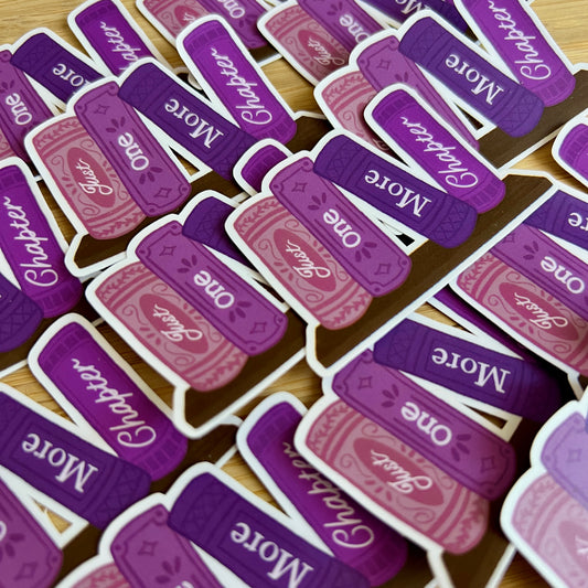 Stack of purple and pink book-themed bookmarks with text on a wooden surface