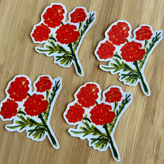 Four red floral stickers on a wooden surface