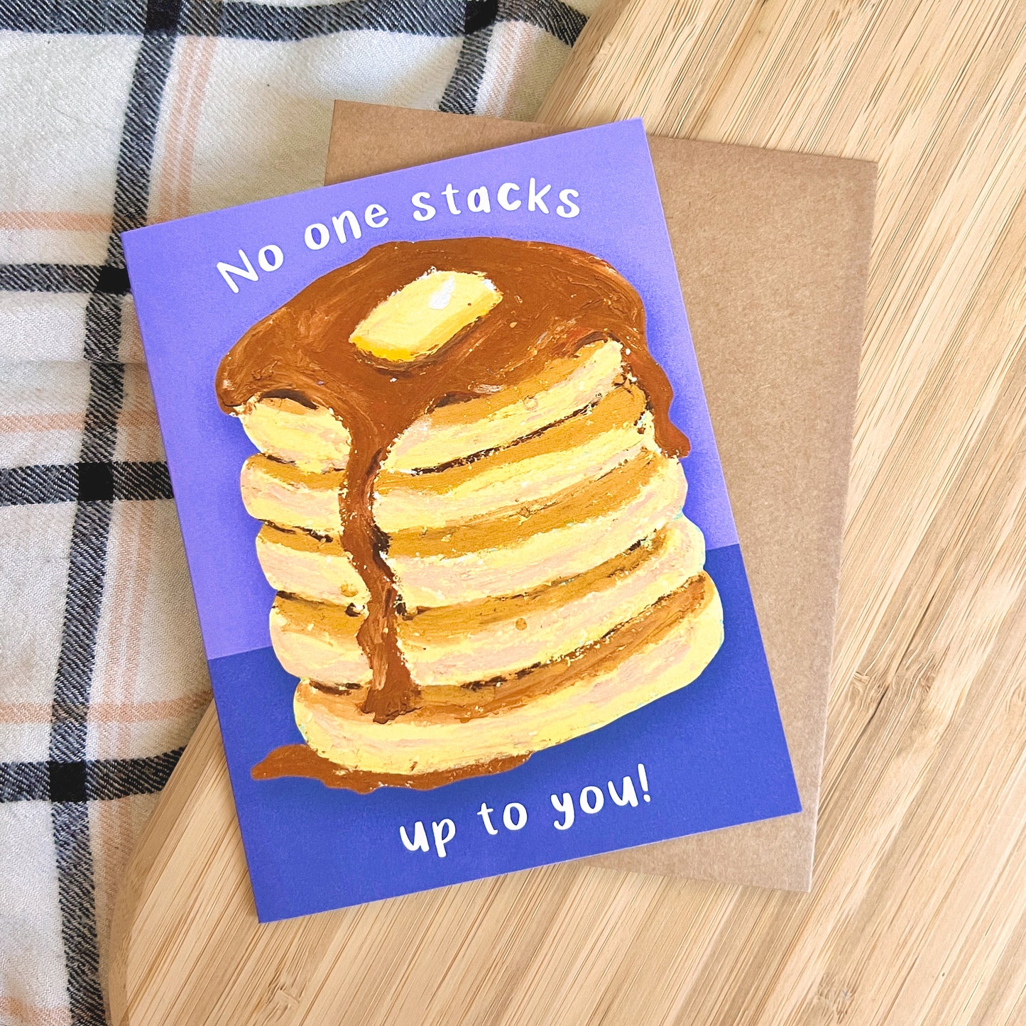 Card with a stack of pancakes and text 'No one stacks up to you!' on a wooden surface