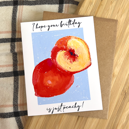 Greeting card with a peach illustration and text on a wooden surface