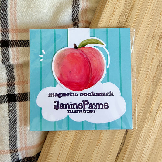 Magnetic bookmark with peach illustration and 'Janine Payne Illustrations' text on a striped fabric background