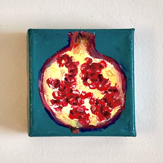 Pomegranate on a square blue canvas with a white background