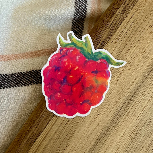 Sticker of a raspberry on a wooden surface with a plaid fabric background