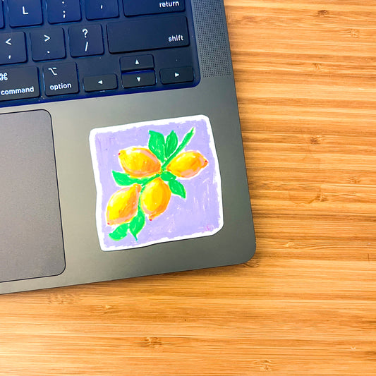 Laptop with a decorative sticker of lemons on a wooden surface