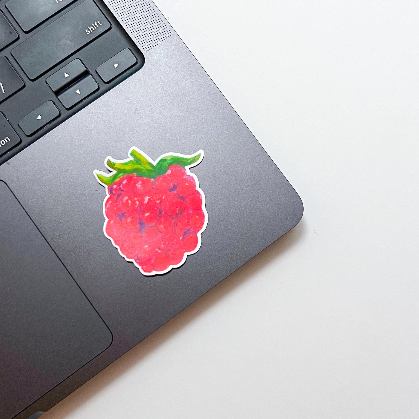 Laptop with a raspberry sticker on a light background