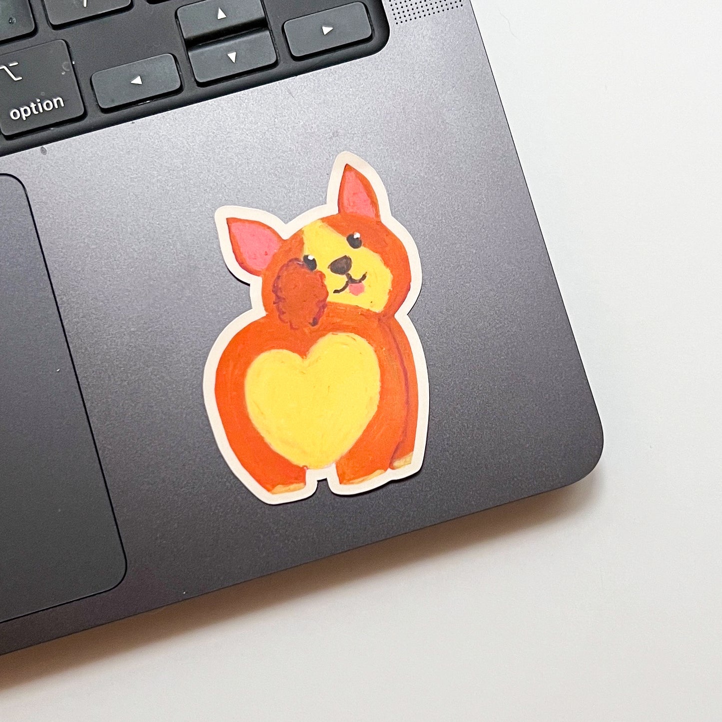 Laptop with a cute dog sticker featuring a heart on a light background
