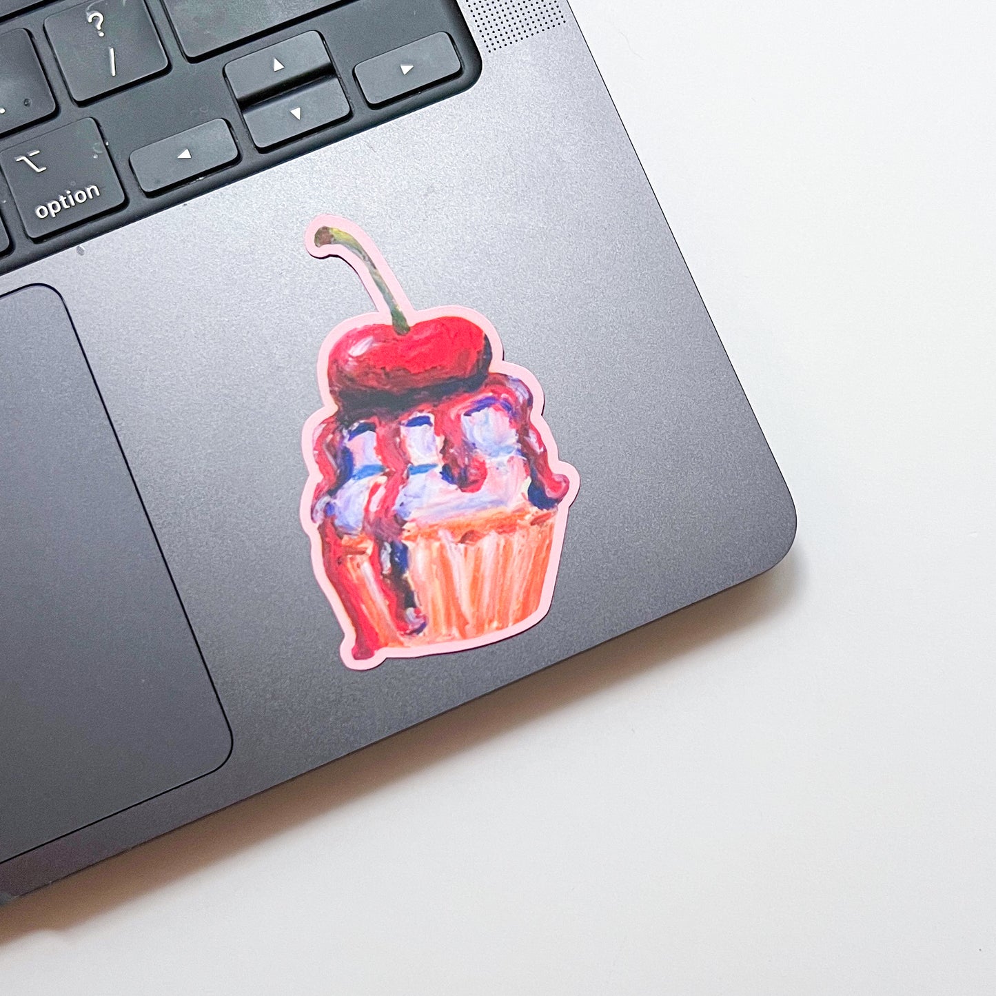 Laptop with a cupcake sticker featuring a cherry on top