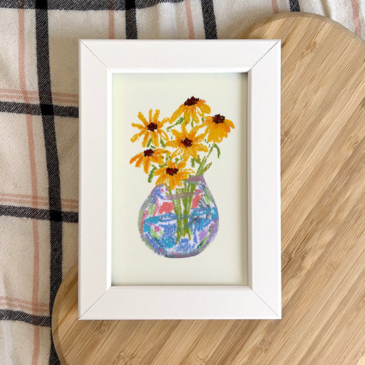 Framed artwork of a colorful vase with flowers on a wooden surface