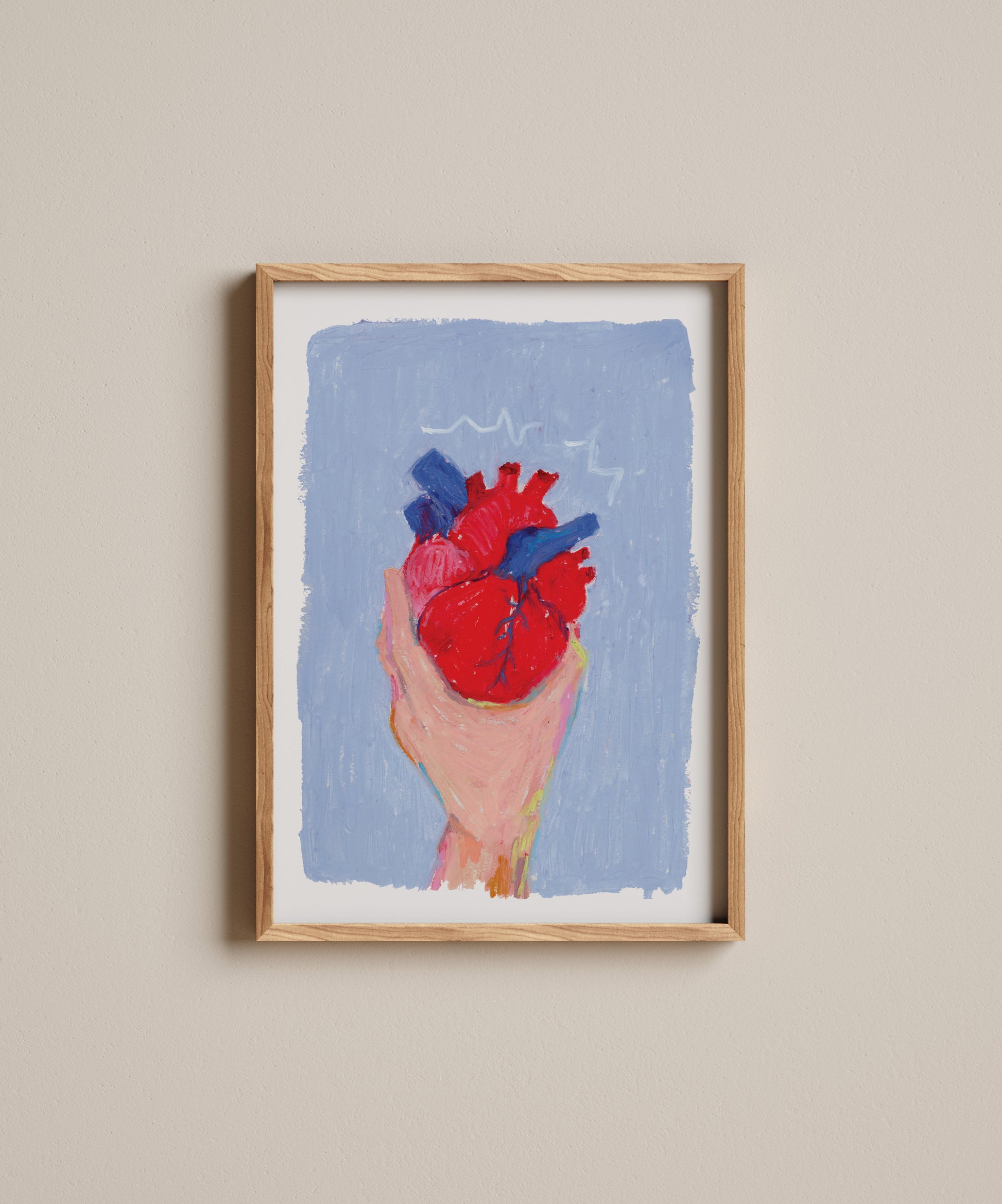 Framed artwork of a hand holding a red heart against a blue background on a beige wall.