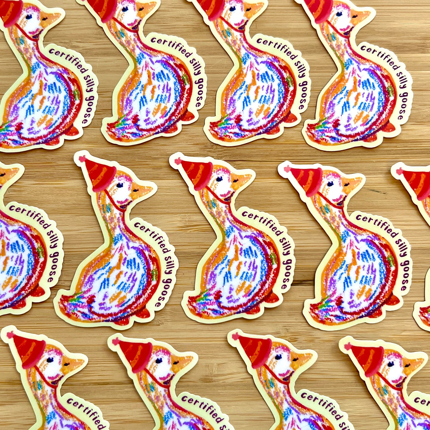 Pattern of colorful goose stickers with 'certified silly goose' text on a wooden surface.