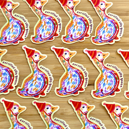 Pattern of colorful goose stickers with 'certified silly goose' text on a wooden surface.