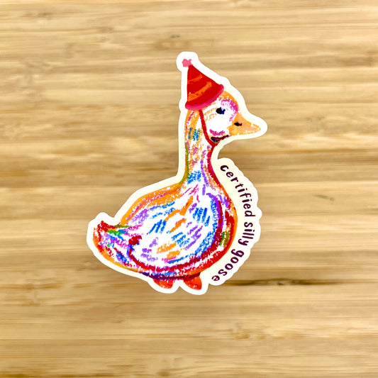 Colorful sticker of a goose wearing a red hat on a wooden surface