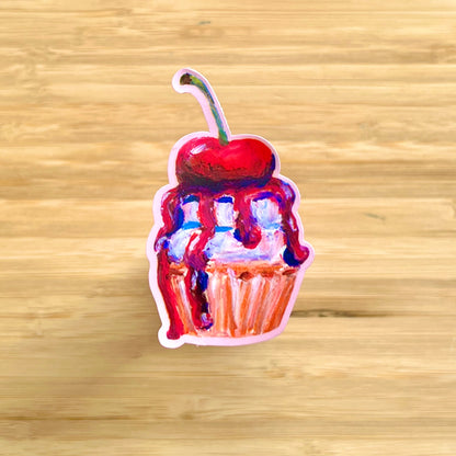 Sticker of a cupcake with a cherry on top on a wooden surface