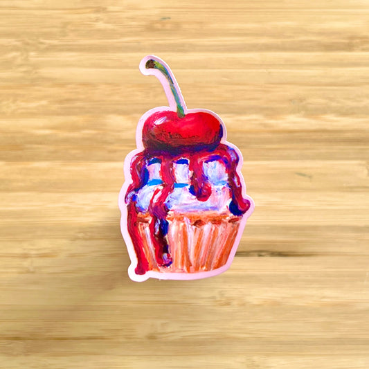Sticker of a cupcake with a cherry on top on a wooden surface