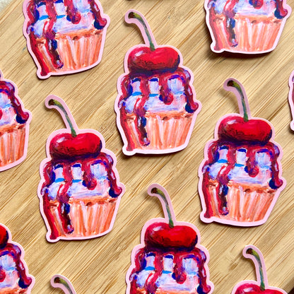 Stickers of cupcakes with cherries and chocolate sauce on a wooden surface