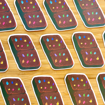 Stickers of a chocolate bar with colorful sprinkles on a wooden surface