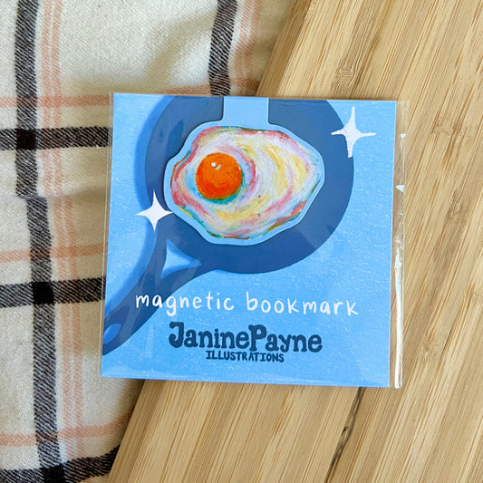 Egg magnetic bookmark with Janine Payne illustrations on a wooden surface
