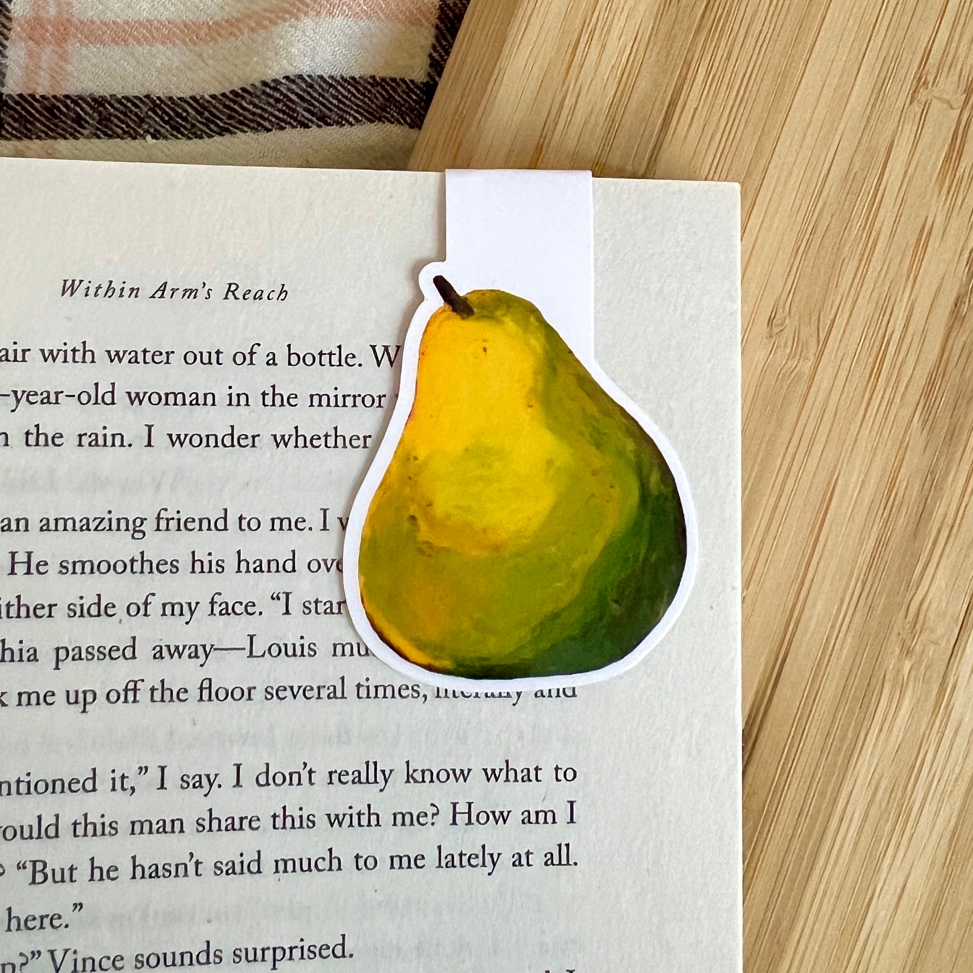 Pear-shaped bookmarker on a book with a wooden surface underneath