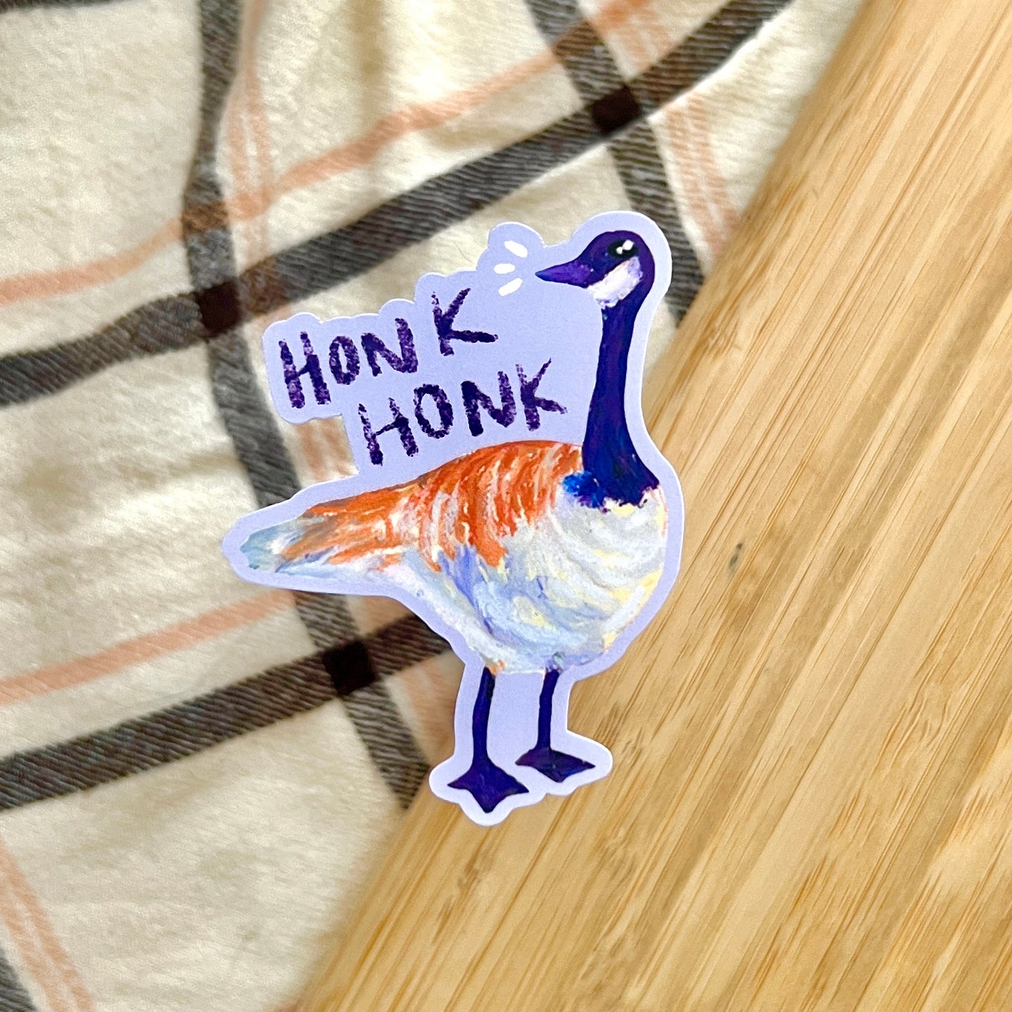Sticker of a goose with 'Honk Honk' text on a plaid fabric background