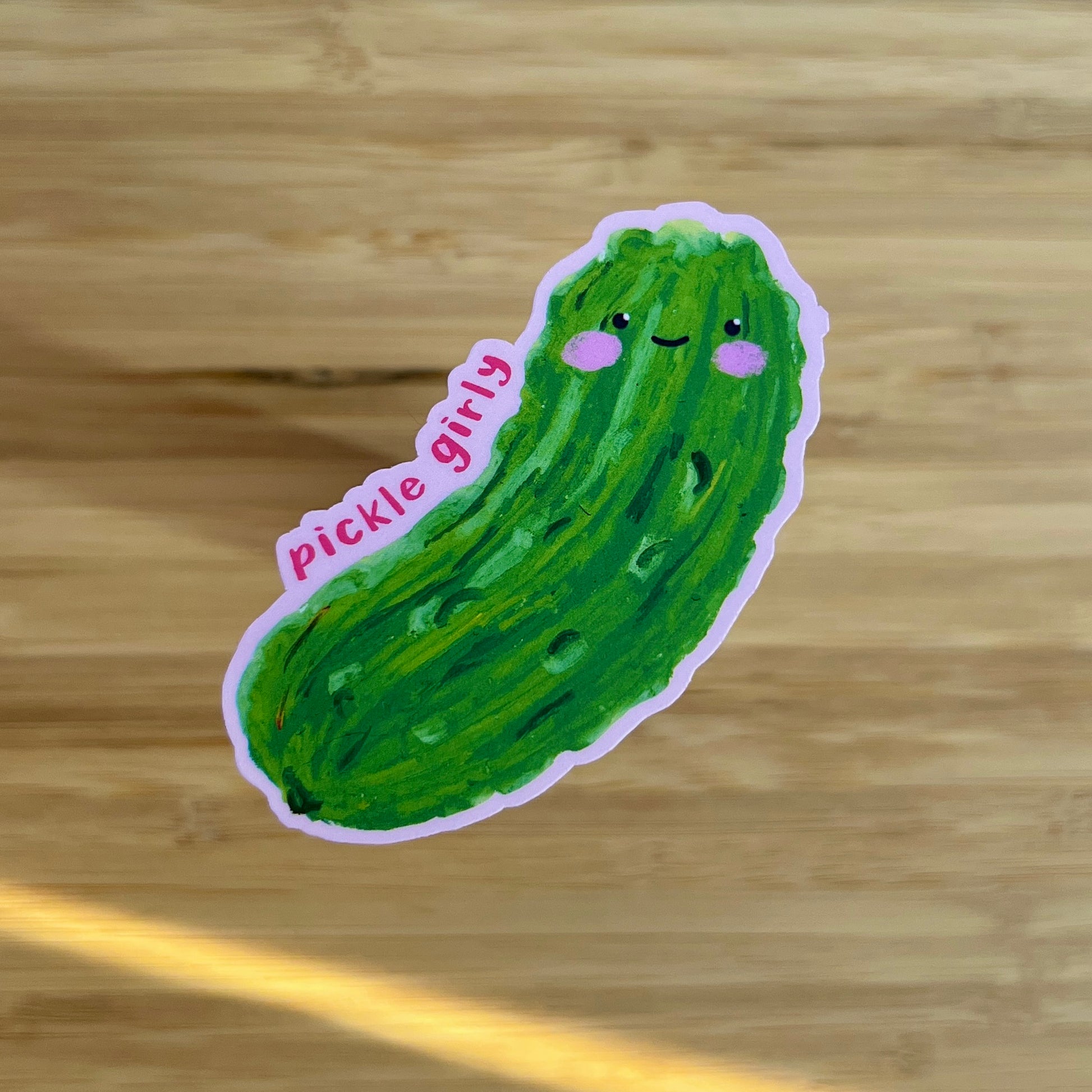 Sticker of a green pickle with a smiling face on a wooden surface