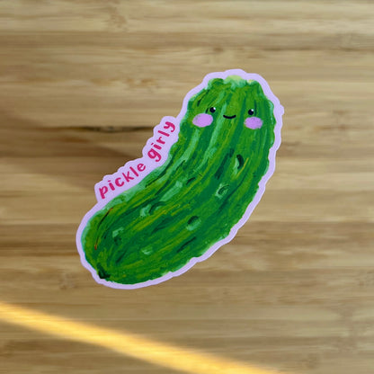 Sticker of a green pickle with a smiling face on a wooden surface