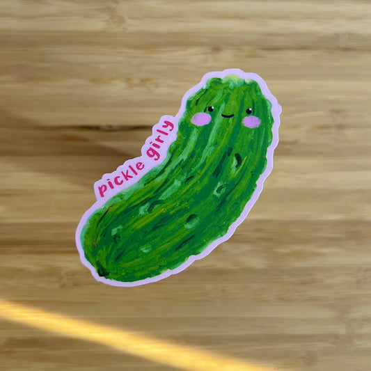 Sticker of a green pickle with a smiling face on a wooden surface
