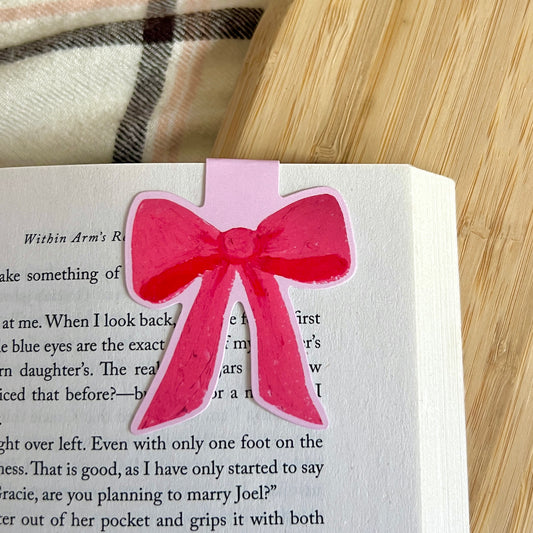 Pink bow bookmark on a book with a plaid fabric background