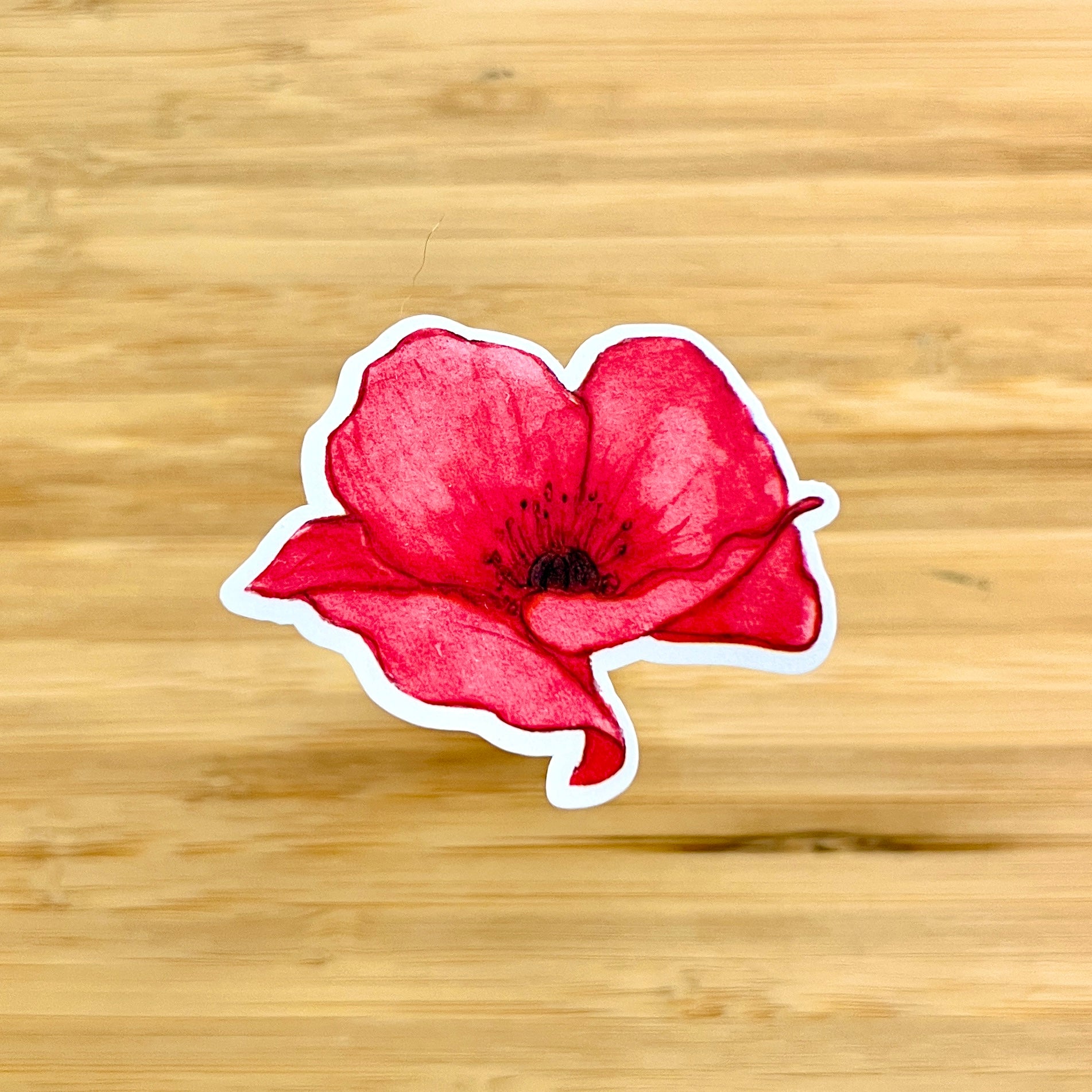 Red flower-shaped sticker on a wooden surface