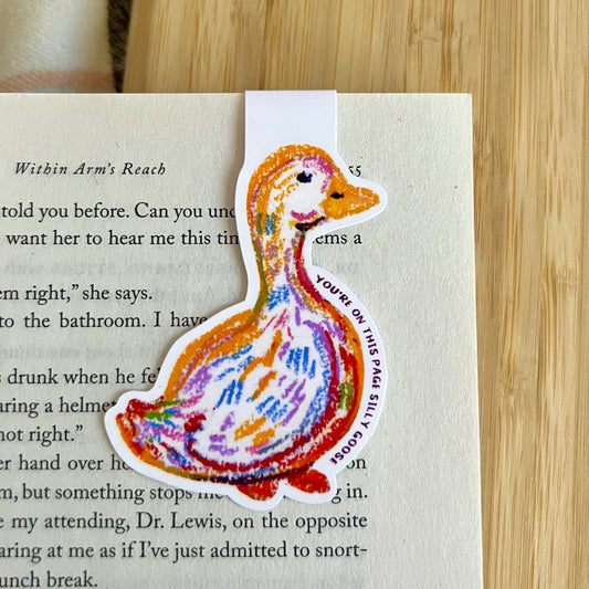 Colorful duck-shaped bookmark on a book page with wooden surface underneath