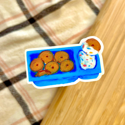 Sticker of a blue tray with cookies and a doll on a checkered fabric background