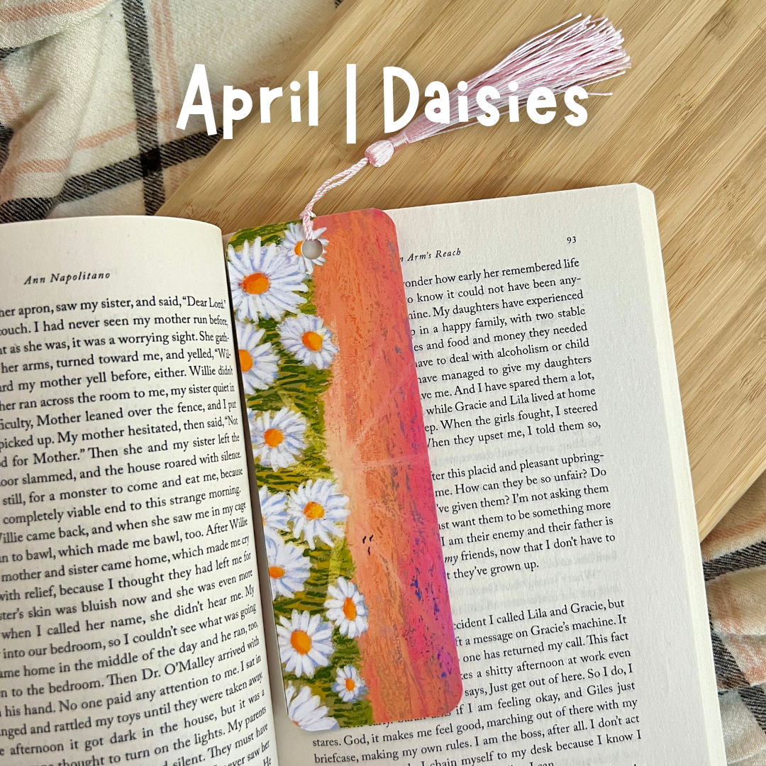 Open book with a decorative bookmark featuring flowers on a wooden surface.
