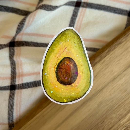 Sticker of an avocado on a wooden surface with a plaid fabric background