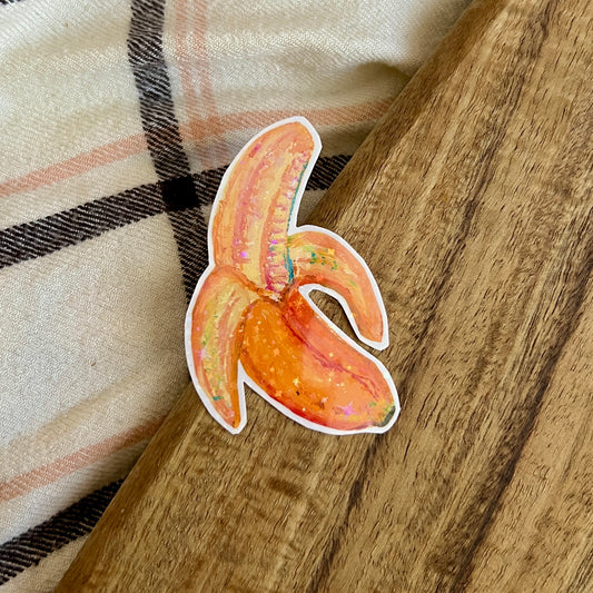 Sticker of a banana on a wooden surface with a plaid fabric background