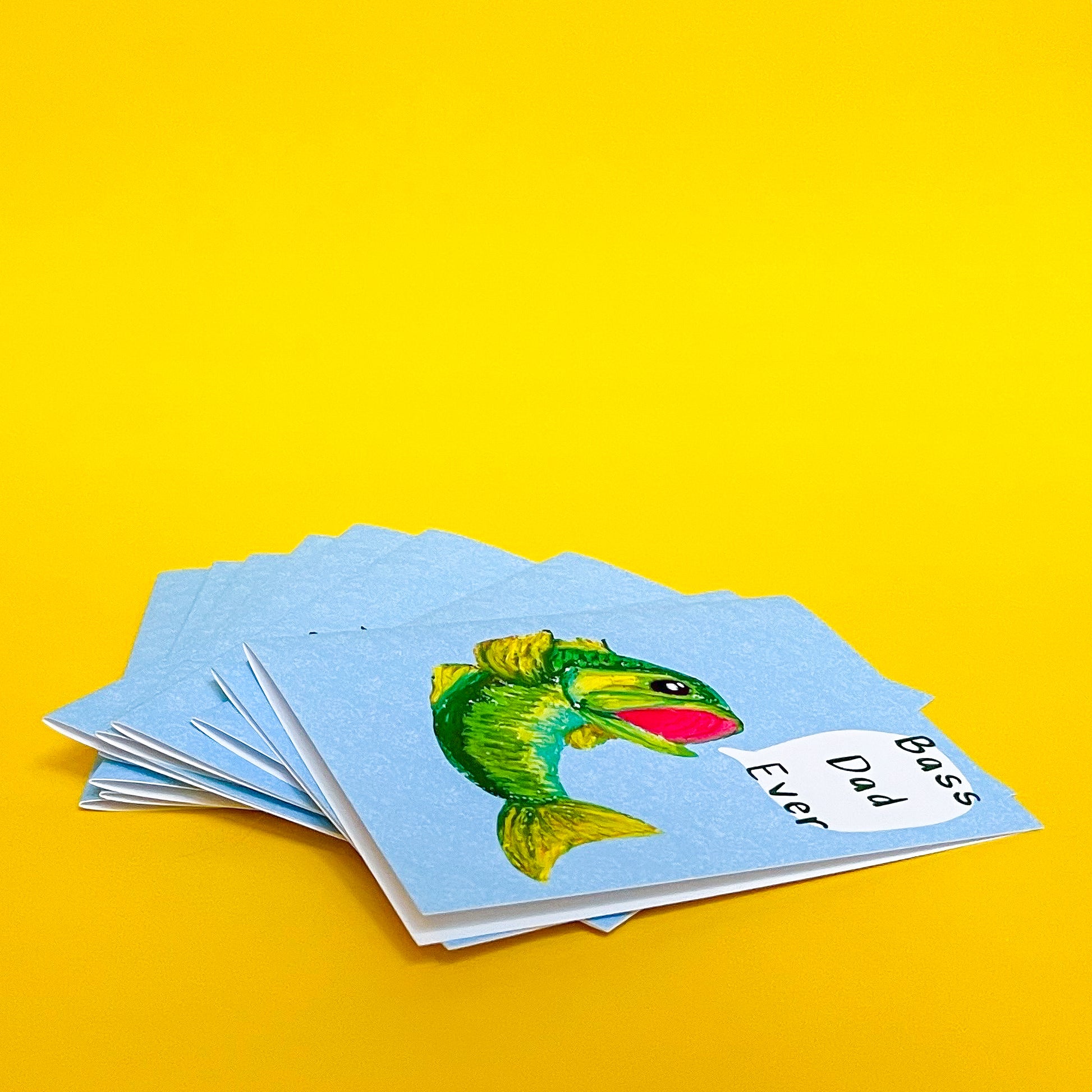 stack of bass dad ever greeting cards with a yellow background