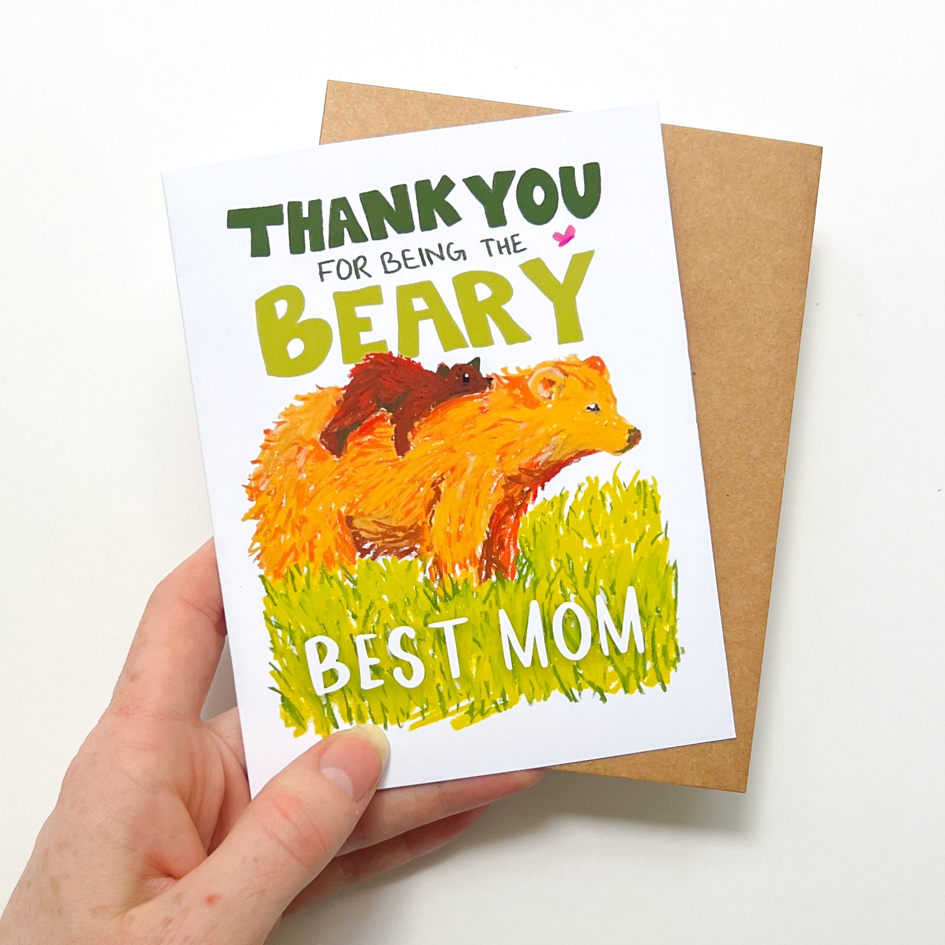 Card with bear illustration and text held by a hand on a white background