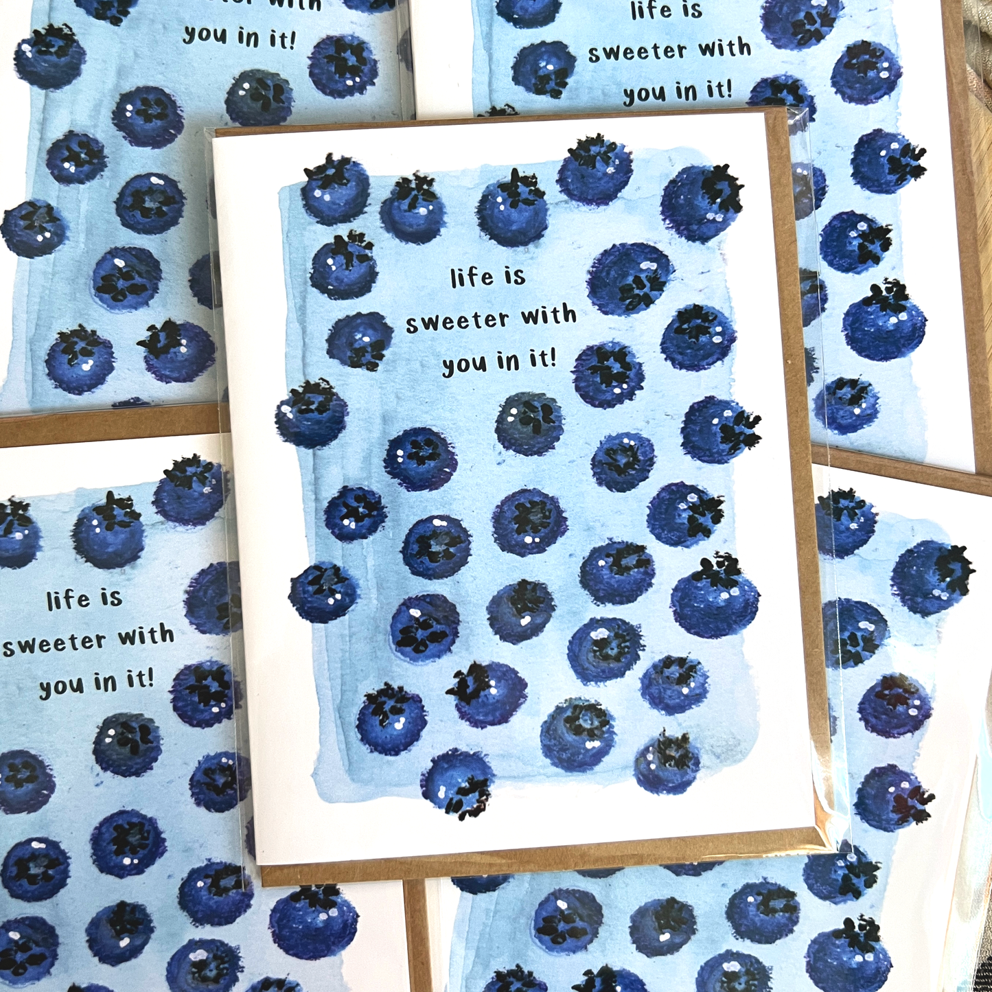 Greeting cards with blueberry pattern and text 'life is sweeter with you in it!' on a matching background.